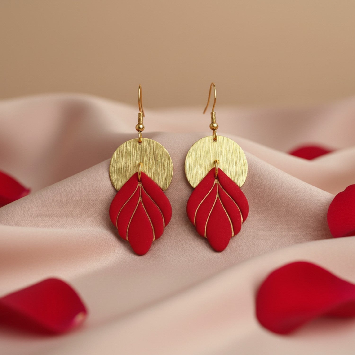 Handmade red and gold statement earrings styled for Valentine’s Day on soft neutral fabric with red rose petals.