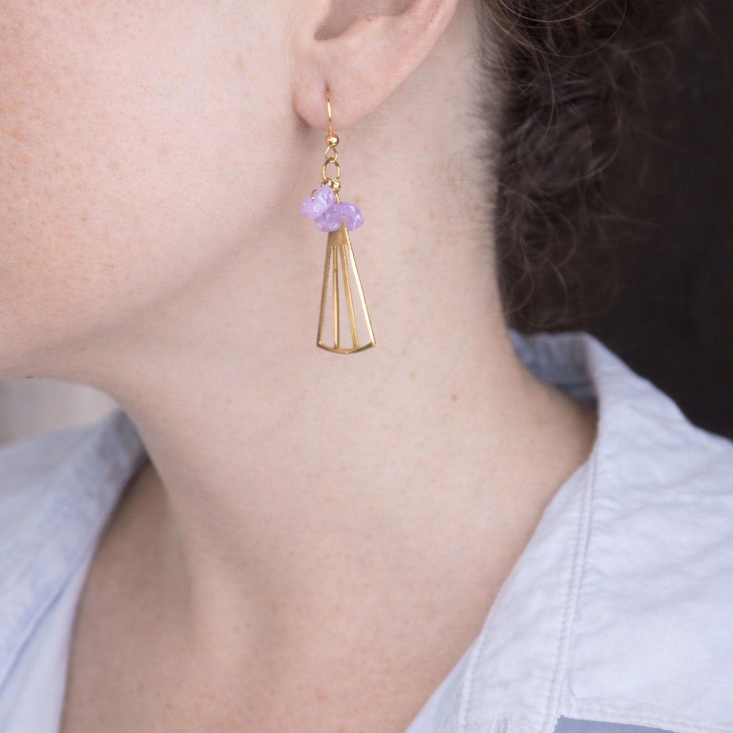 Gold earrings with amethyst stones worn by a woman