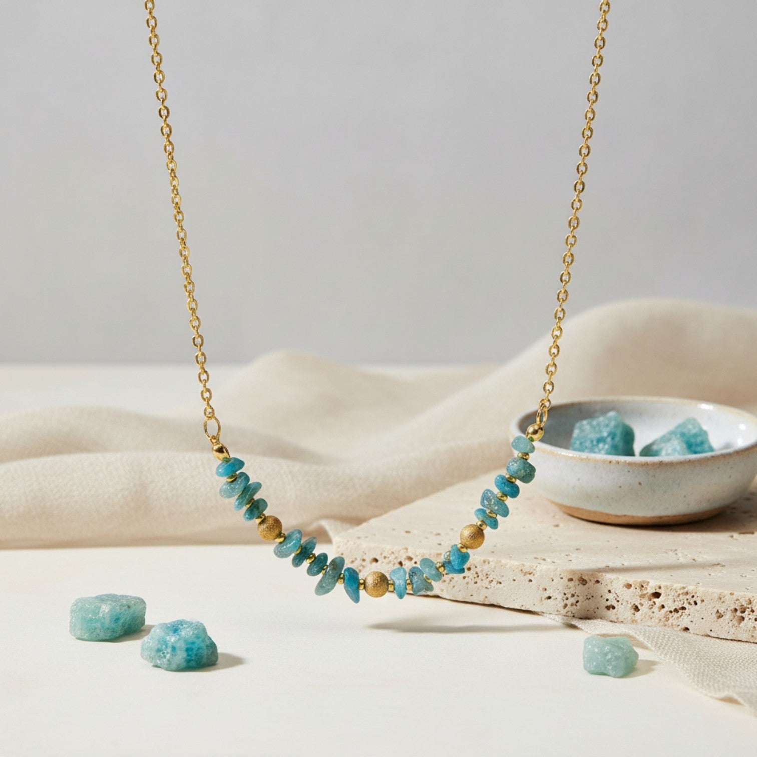 Blue Apatite and golden beads necklace on a minimalist background.