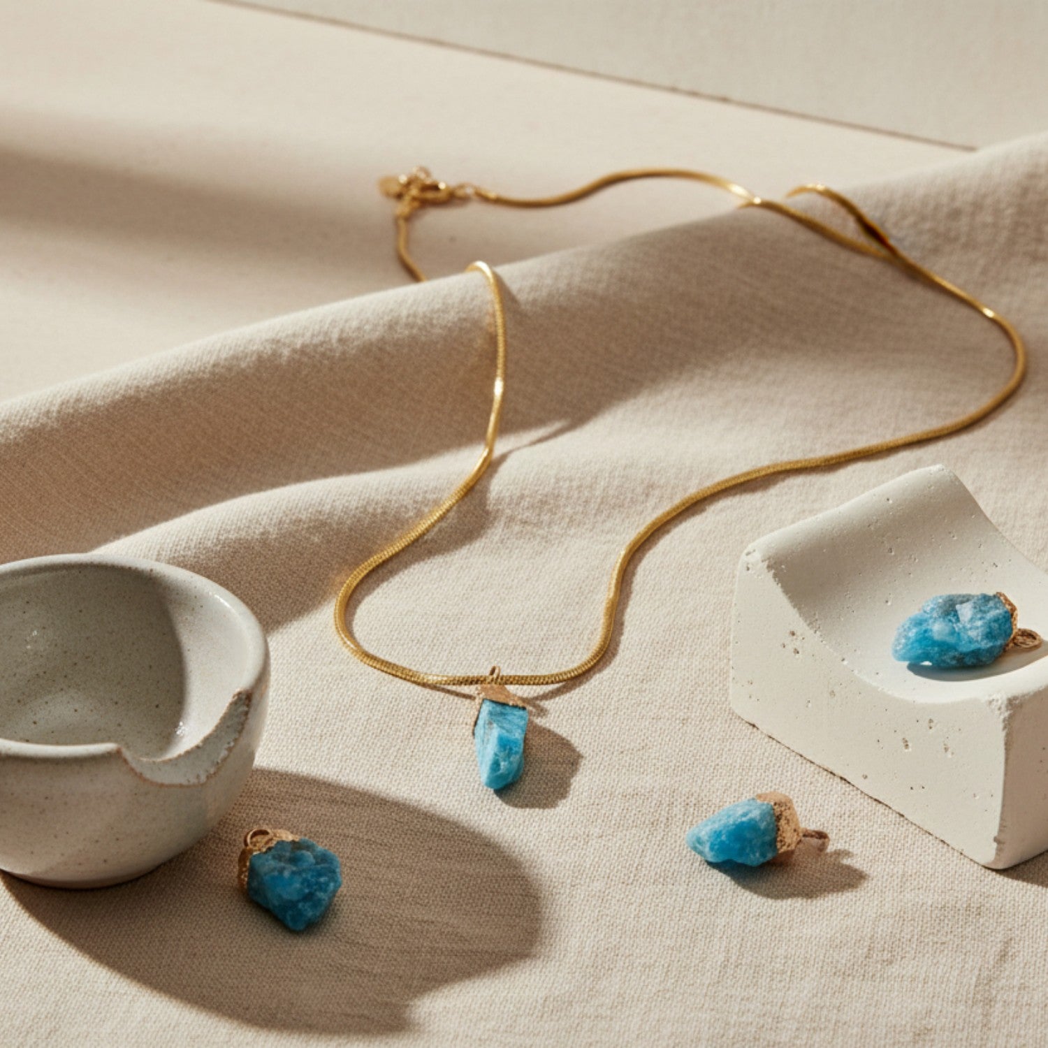 Gold necklace with blue apatite pendant on beige fabric
