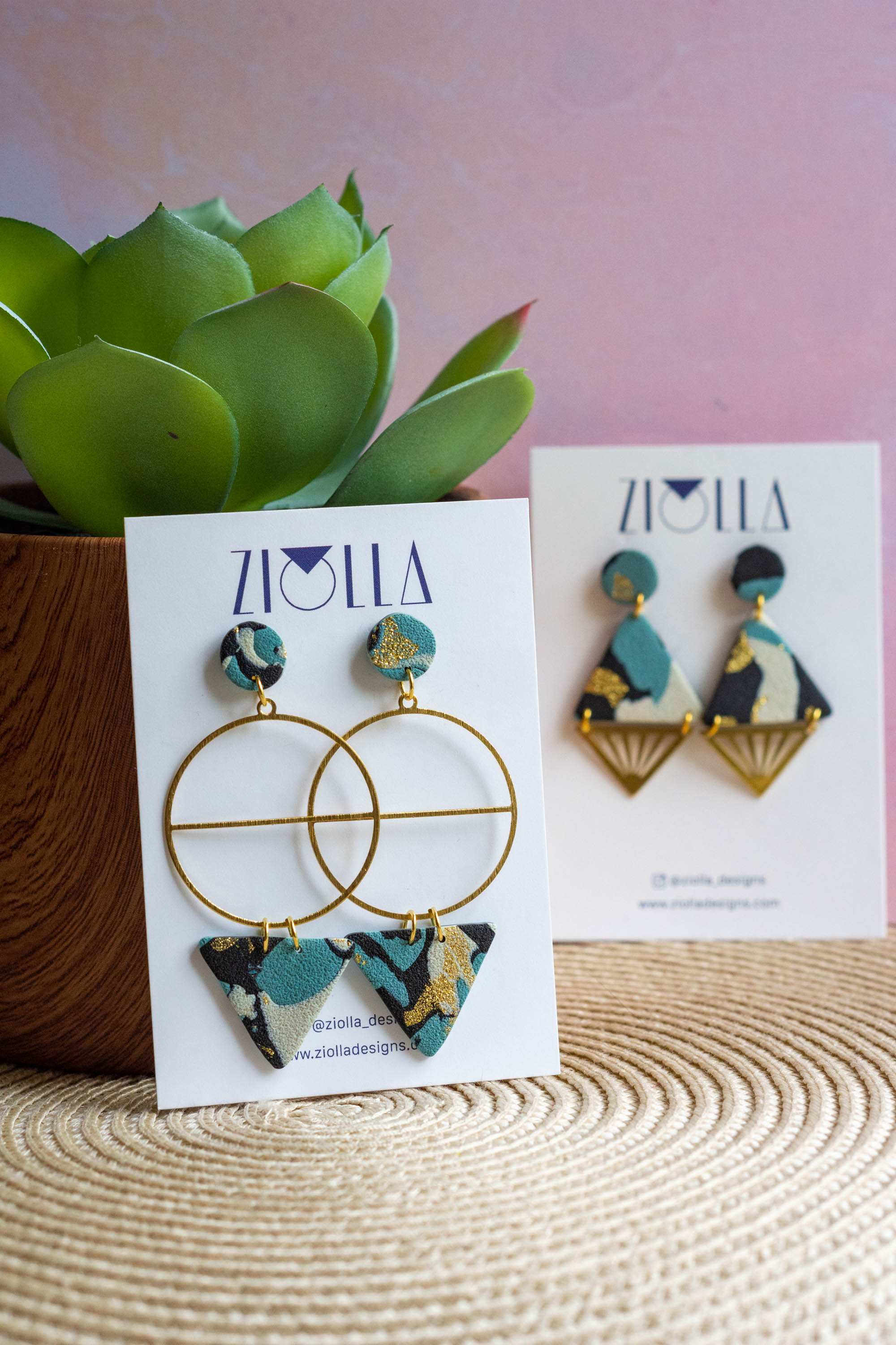 Handmade geometric statement earrings by Ziolla Designs, featuring gold-plated circular hoops with marbled teal, black and gold polymer clay details, displayed on a branded jewellery card