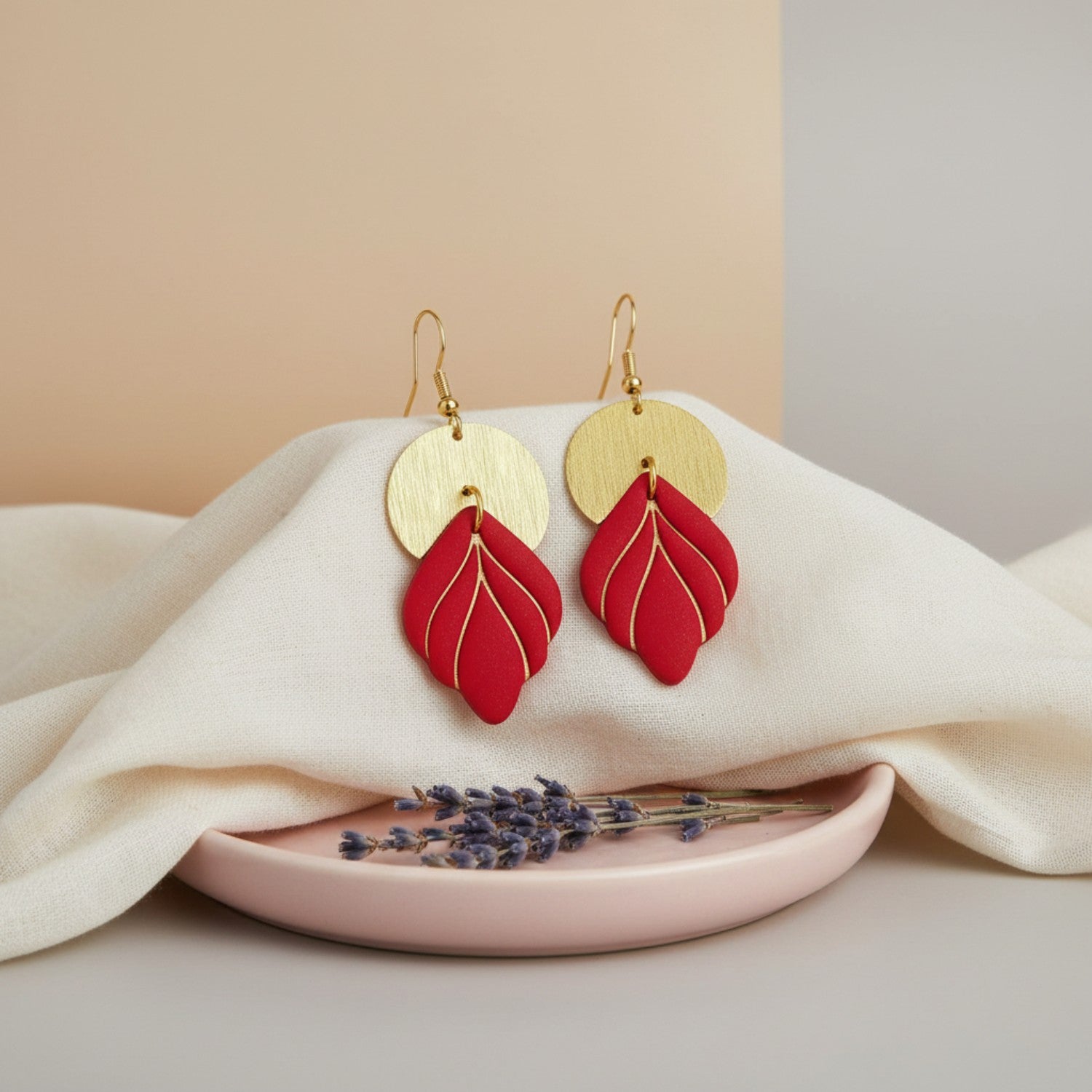 Red earrings with gold accents on a white fabric background
