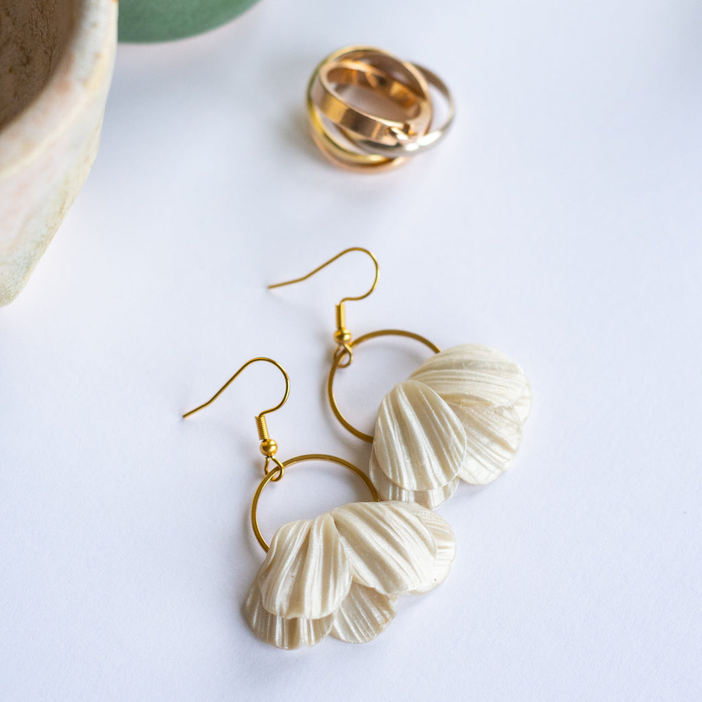 Flower Bridal  earrings on a white background and gold wedding rings.