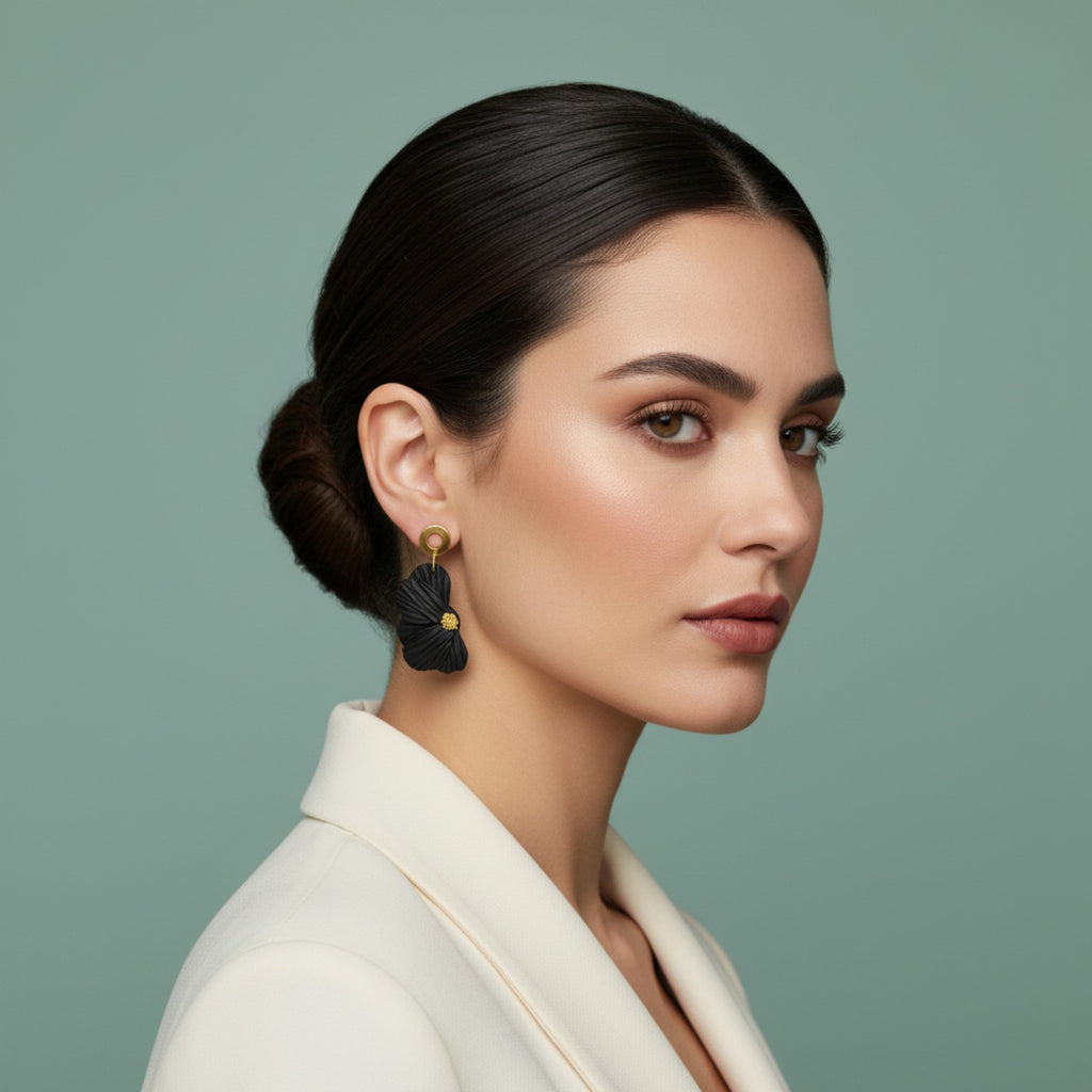 Woman wearing black flower earrings and a white blazer with a green background