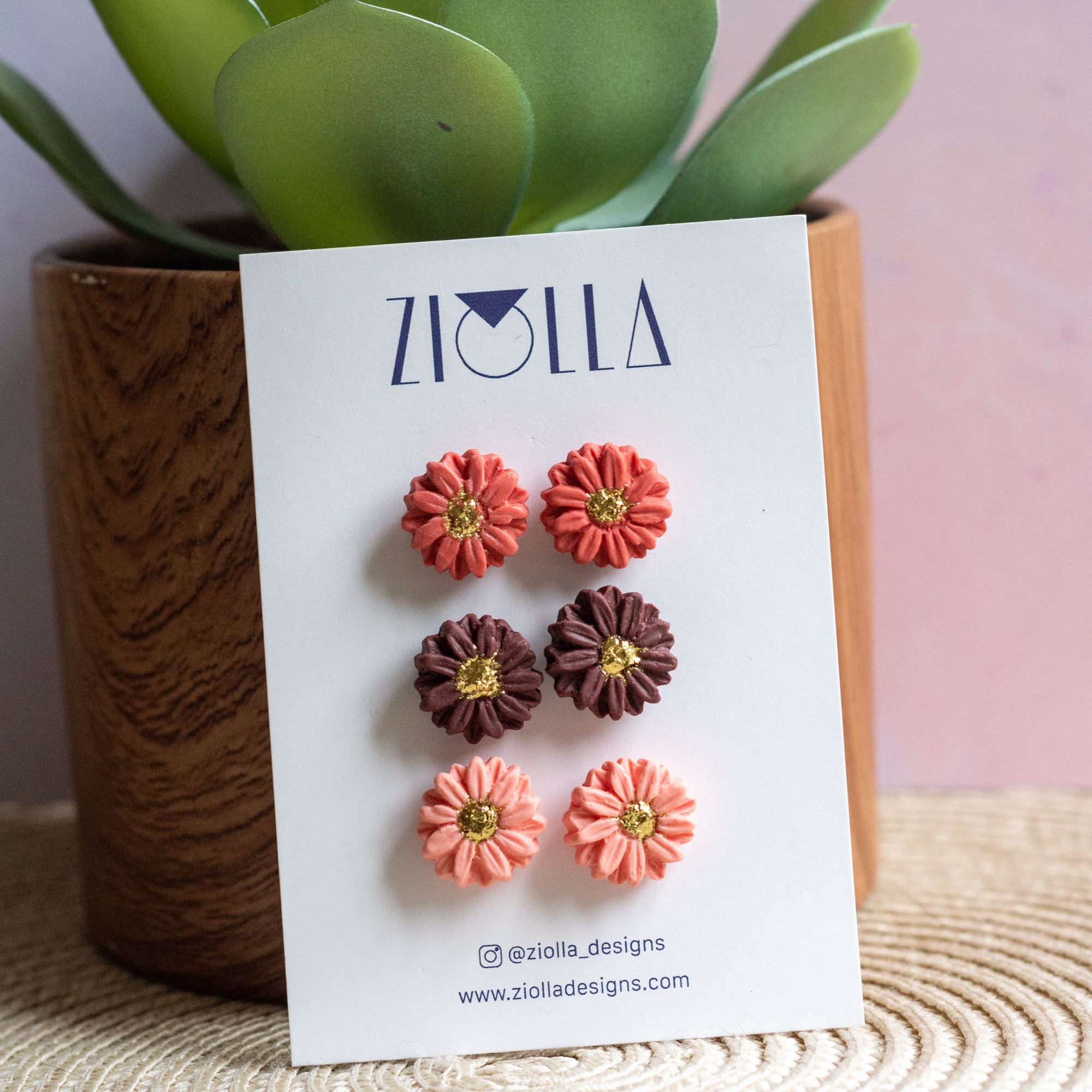 Flower earrings on a card with a plant in the background
