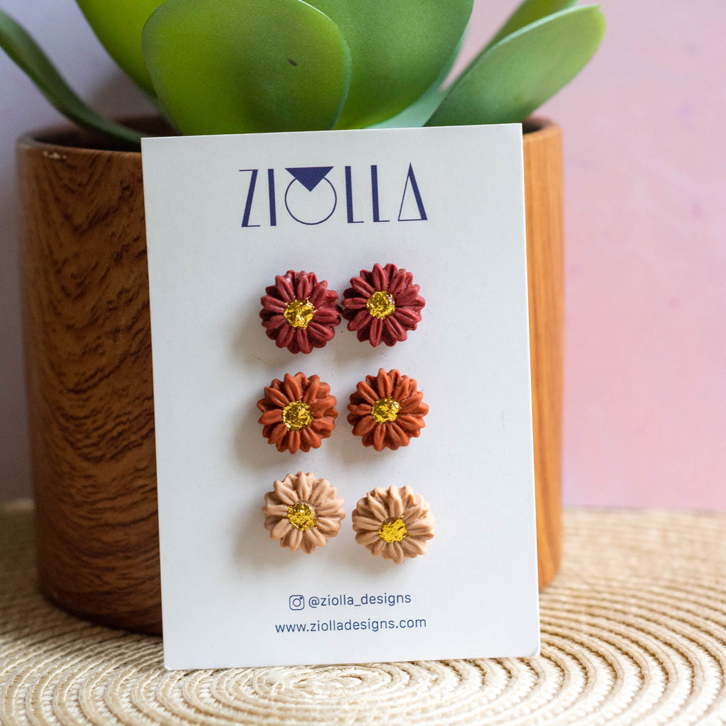 Set of flower earrings on a Ziolla branded card with a plant in the background