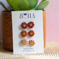 Set of flower earrings on a Ziolla branded card with a plant in the background