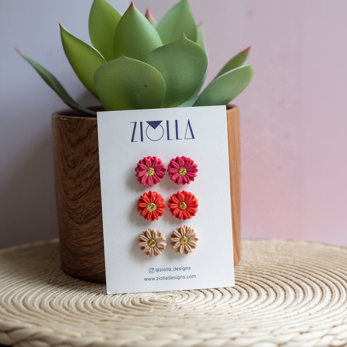 Flower earrings on a card with a plant in the background