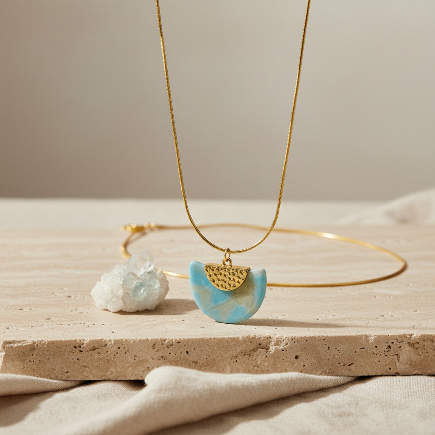  Necklace with a Blue Faux Stone and gold pendant on a neutral background