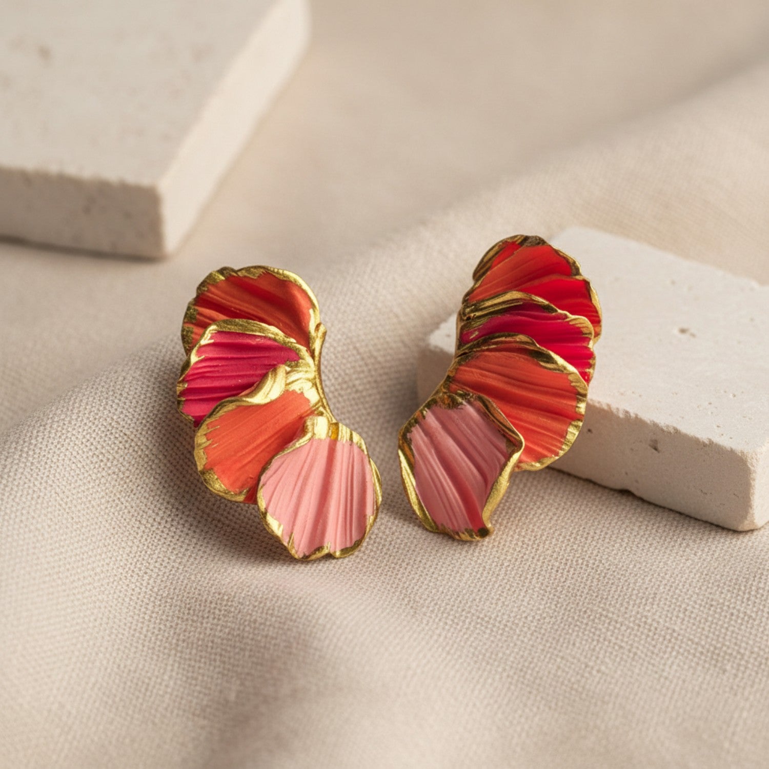 Pair of earrings with red and pink design on a beige surface