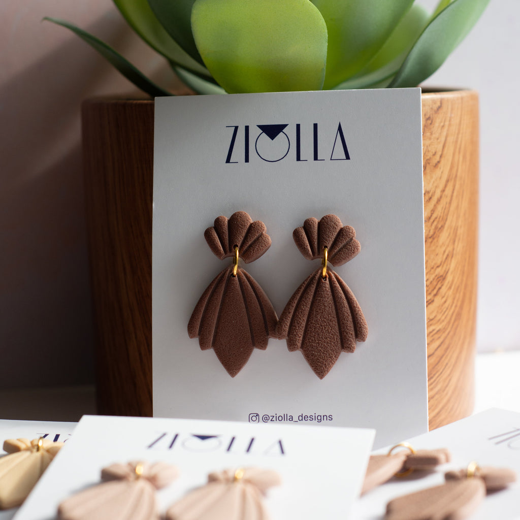 Brown earrings on a ZIOLLA branded card with a plant in the background