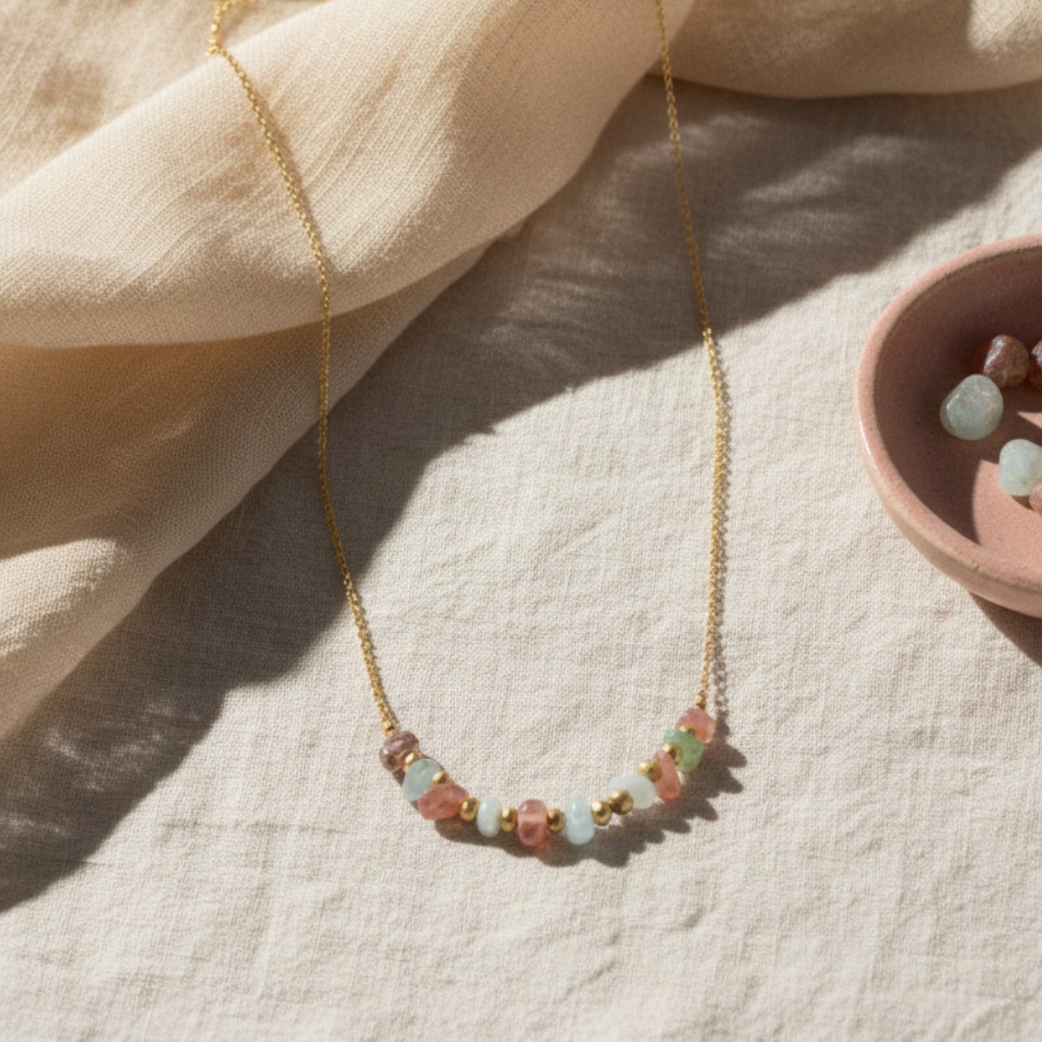 Necklace with rose quartz and aquamarine beads on a light fabric background