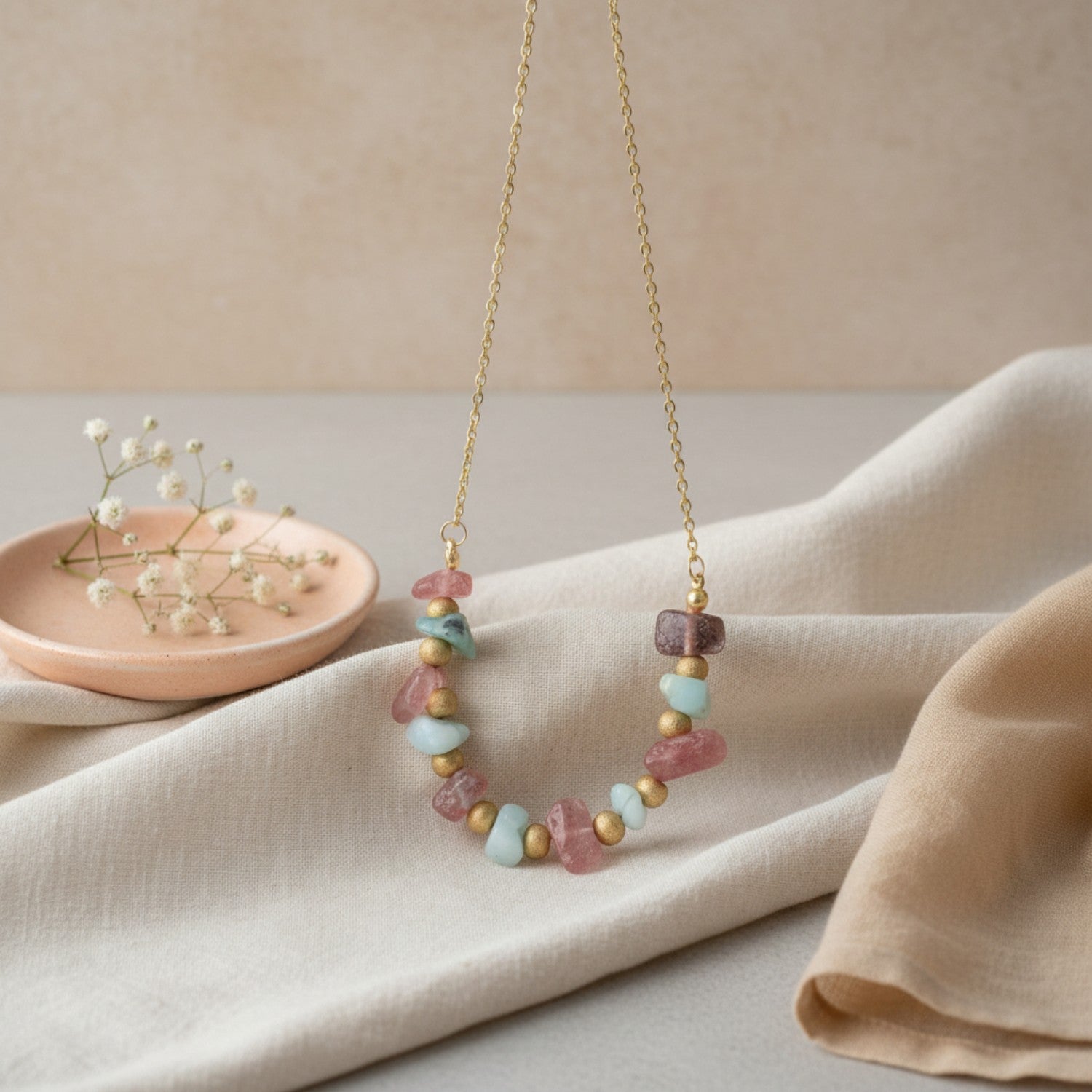 Rose Quartz and Aquamarine beaded necklace on a beige fabric background