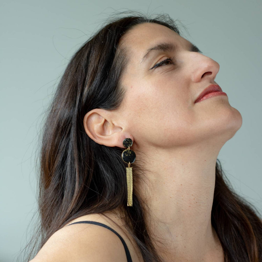 Woman wearing gold earrings with a neutral background