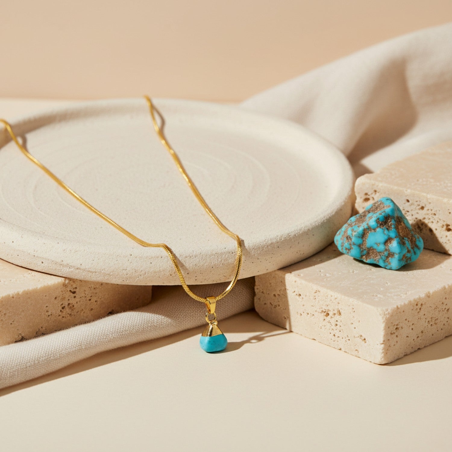 Gold necklace with turquoise pendant on beige stones