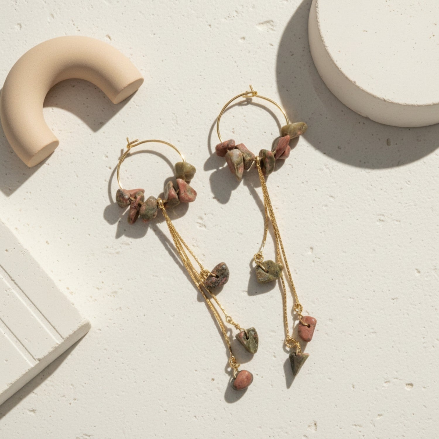 Pair of unakite earrings with stone beads on a beige surface