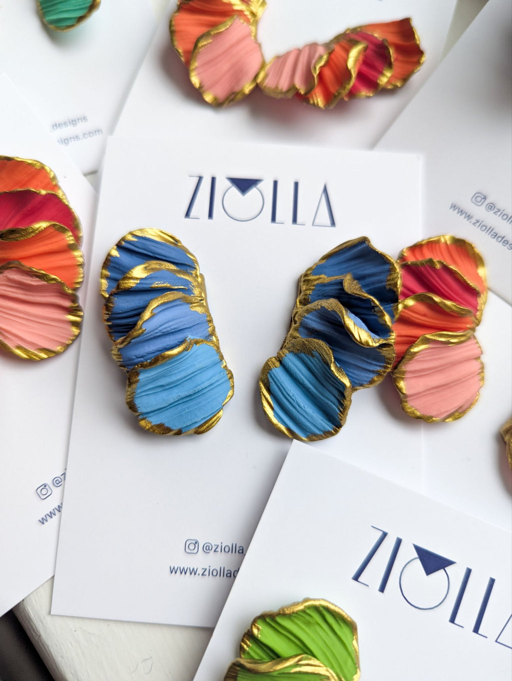 Colorful earrings with gold accents on a Ziolia branded card.